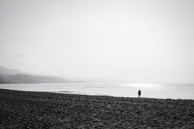 Silhouette man standing on beach against clear sky