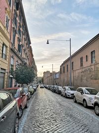 Cars on street amidst buildings in city against sky