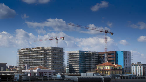 Cranes in city against sky