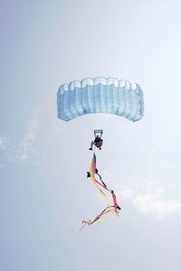 Low angle view of man paragliding against sky