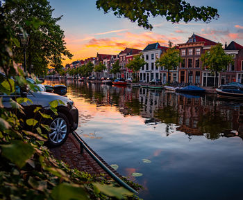 Canal amidst buildings against sky during sunset