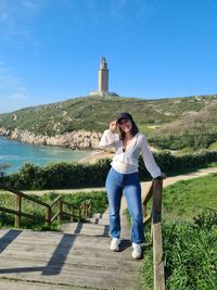 Rear view of woman standing by railing against sky