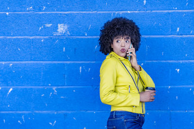 Mid adult woman standing against blue wall