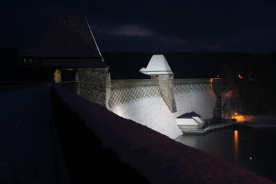 View of swimming pool against building at night