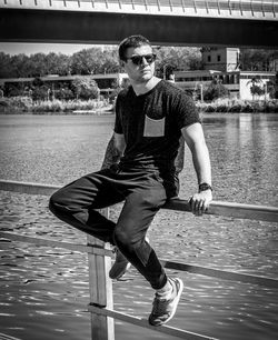 Full length portrait of young man standing against lake