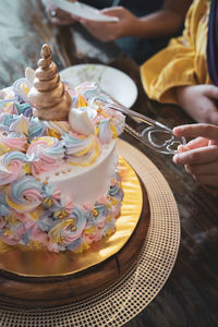 Midsection of person cutting a birthday cake on table