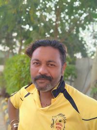 Portrait of mature man standing against plants