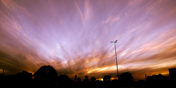 Low angle view of silhouette street light against dramatic sky