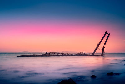 Silhouette ship on sea against sky during sunset