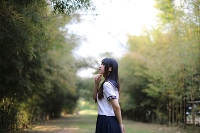 Side view of woman standing against trees