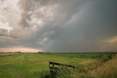 Scenic view of field against cloudy sky