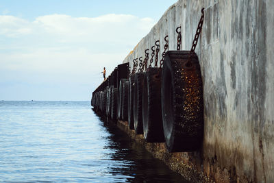 Man standing on tire against sea