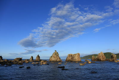 Rocks in sea against blue sky