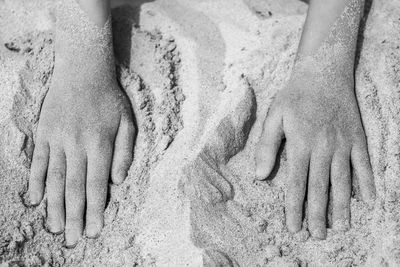 Cropped hands of child on sand at beach