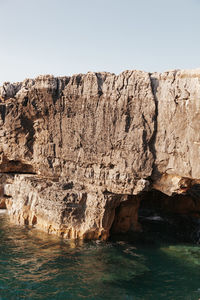 Rock formations in sea against clear sky