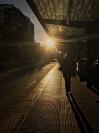 Rear view of silhouette man walking on railroad station