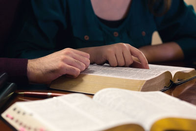 Midsection of man reading book on table