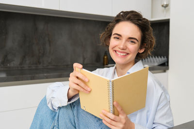 Portrait of smiling young woman holding book