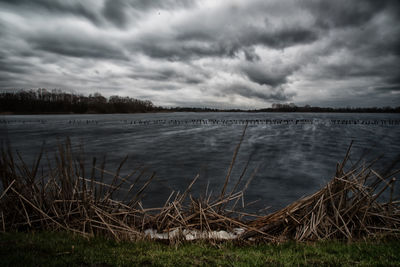 Scenic view of lake against cloudy sky