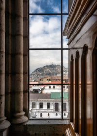 Buildings against sky seen through glass window