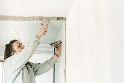 Woman putting cement on ceiling