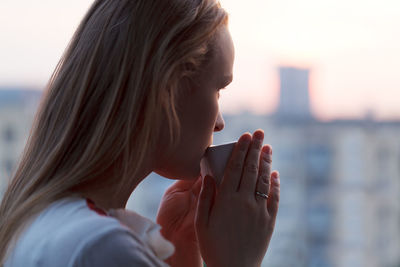 Close-up of woman having coffee by window