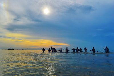 Silhouette people on beach against sky during sunset