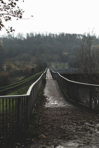 Footbridge amidst trees against sky