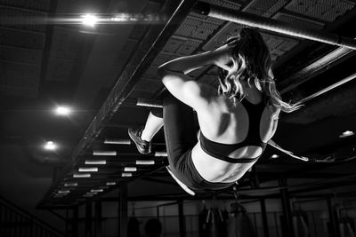 Woman on boxing training doing crunches on monkey bar