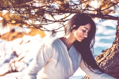 Side view of a smiling young woman against trees