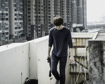 Young man moving up on building terrace with camera