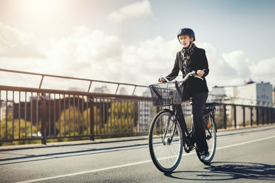Businesswoman riding bicycle on bridge in city