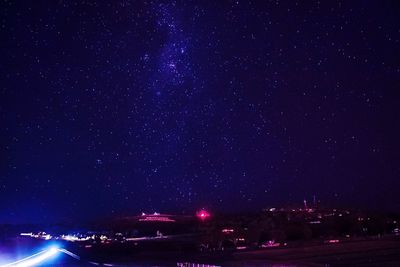 Cars on illuminated road against sky at night