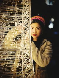 Portrait of young woman standing against blurred background