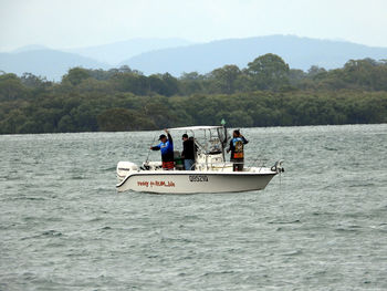 People in boat sailing on sea against sky