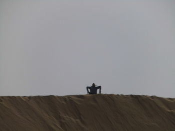 Silhouette man standing on desert against clear sky