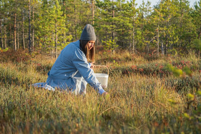 Autumn berries picking. young woman on swamp searching for ripe cranberry spend weekend outside city
