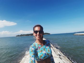 Portrait of smiling woman at beach against sky during summer