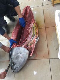 High angle view of people cutting fish on tiled floor at market