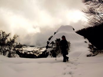 Woman hiking on snow at mt etna against cloudy sky