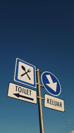 Low angle view of road sign against blue sky