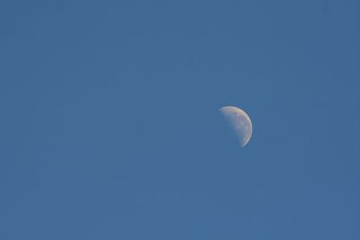 Low angle view of moon against clear blue sky