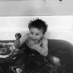 Happy boy gesturing while taking bath in bathtub