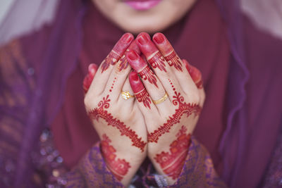 Midsection of bride with henna tattoo praying during wedding