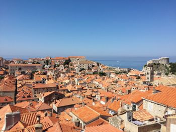 High angle view of houses by sea against clear blue sky