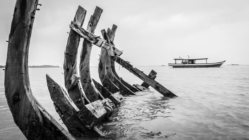 Damaged pier and boat in sea against clear sky