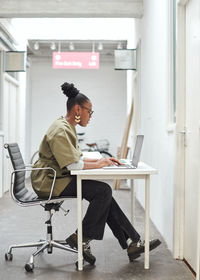 Side view of businesswoman sitting at desk in office