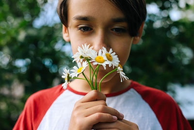 Close-up of boy smelling flowers