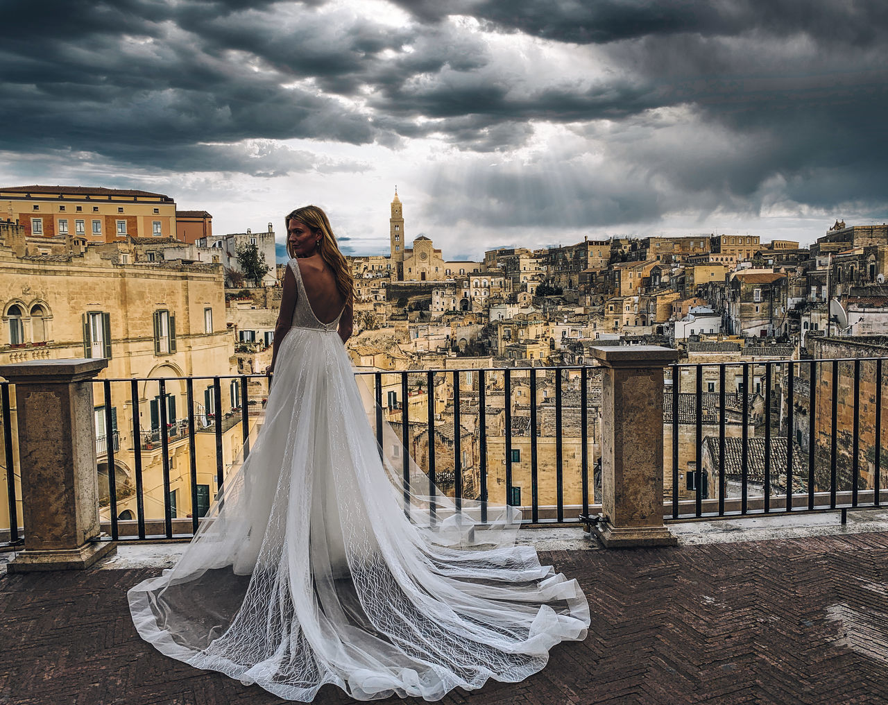 WOMAN STANDING BY BUILDING AGAINST CLOUDY SKY