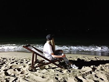 Rear view of man sitting on beach